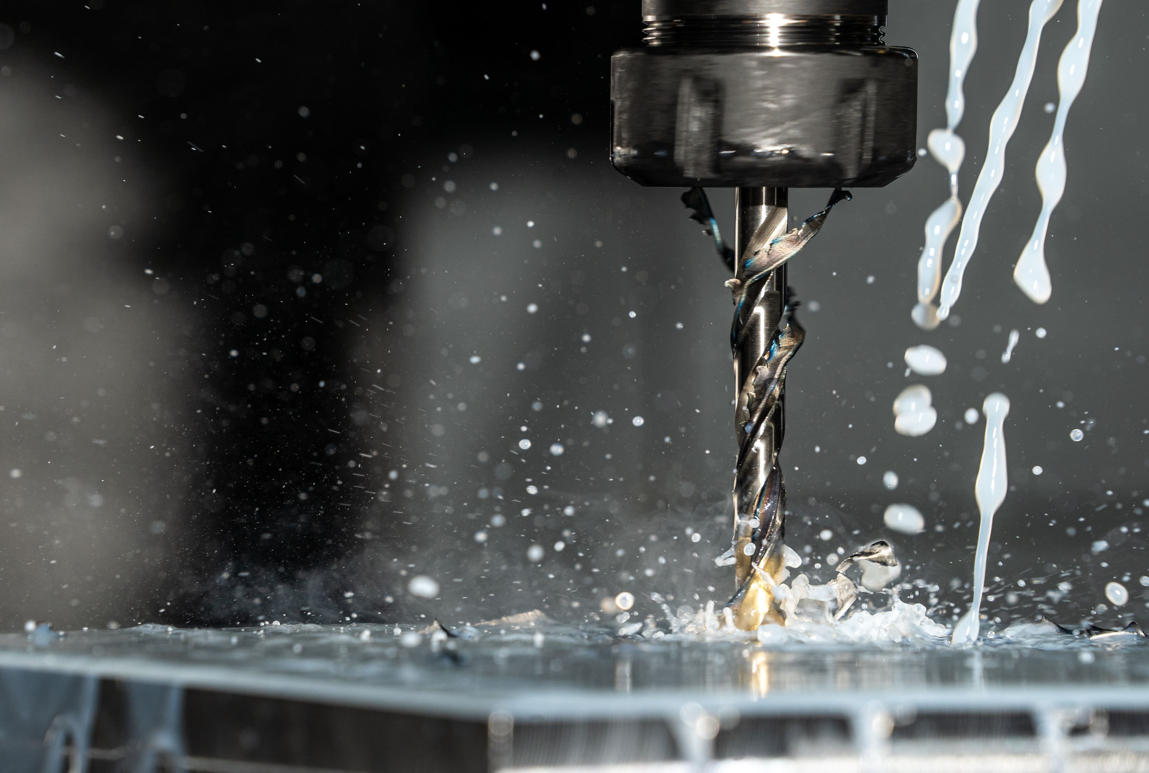 Drill cutting a metal workpiece with coolant and metal chips