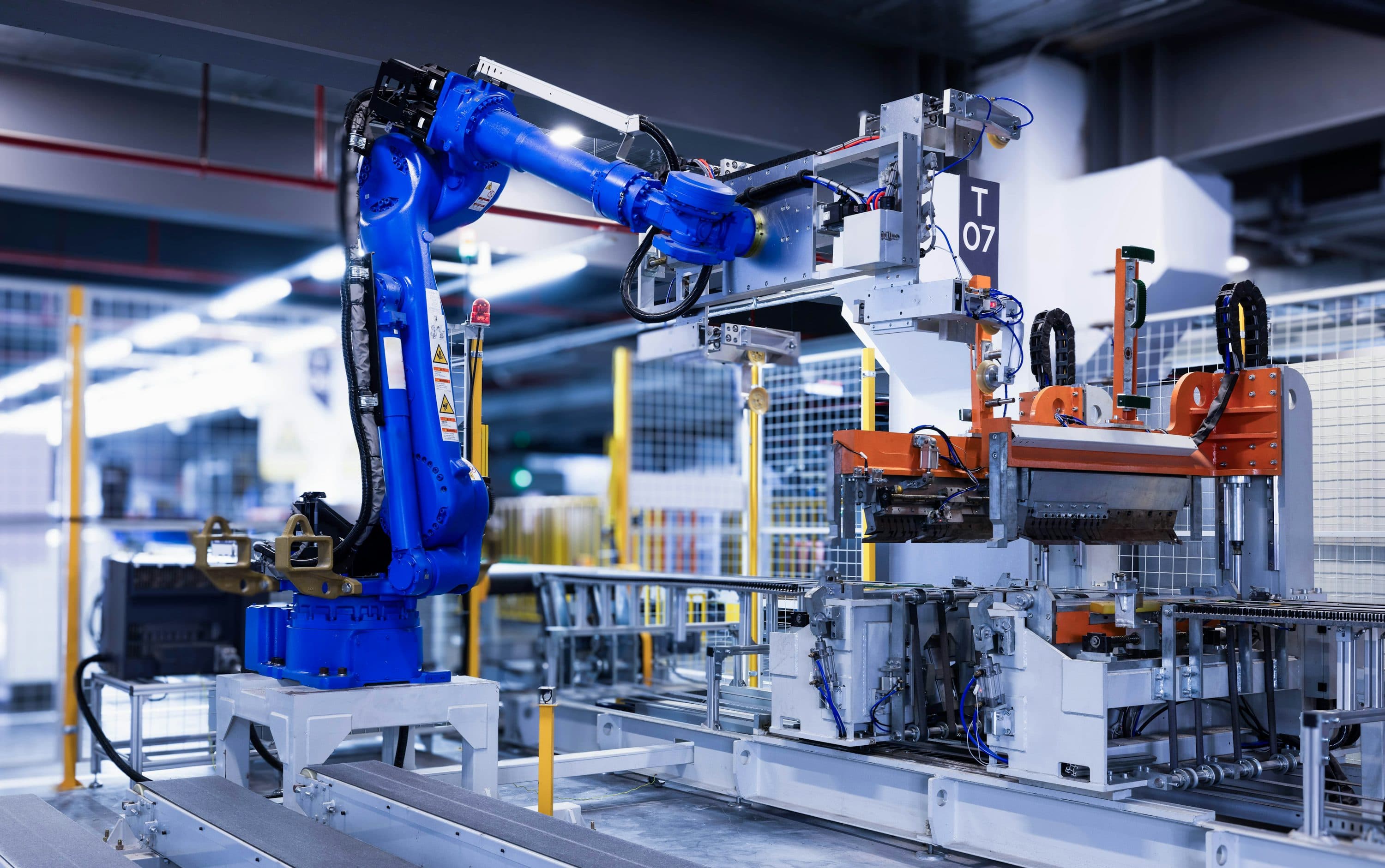 Blue industrial robot handling a panel in a factory cell