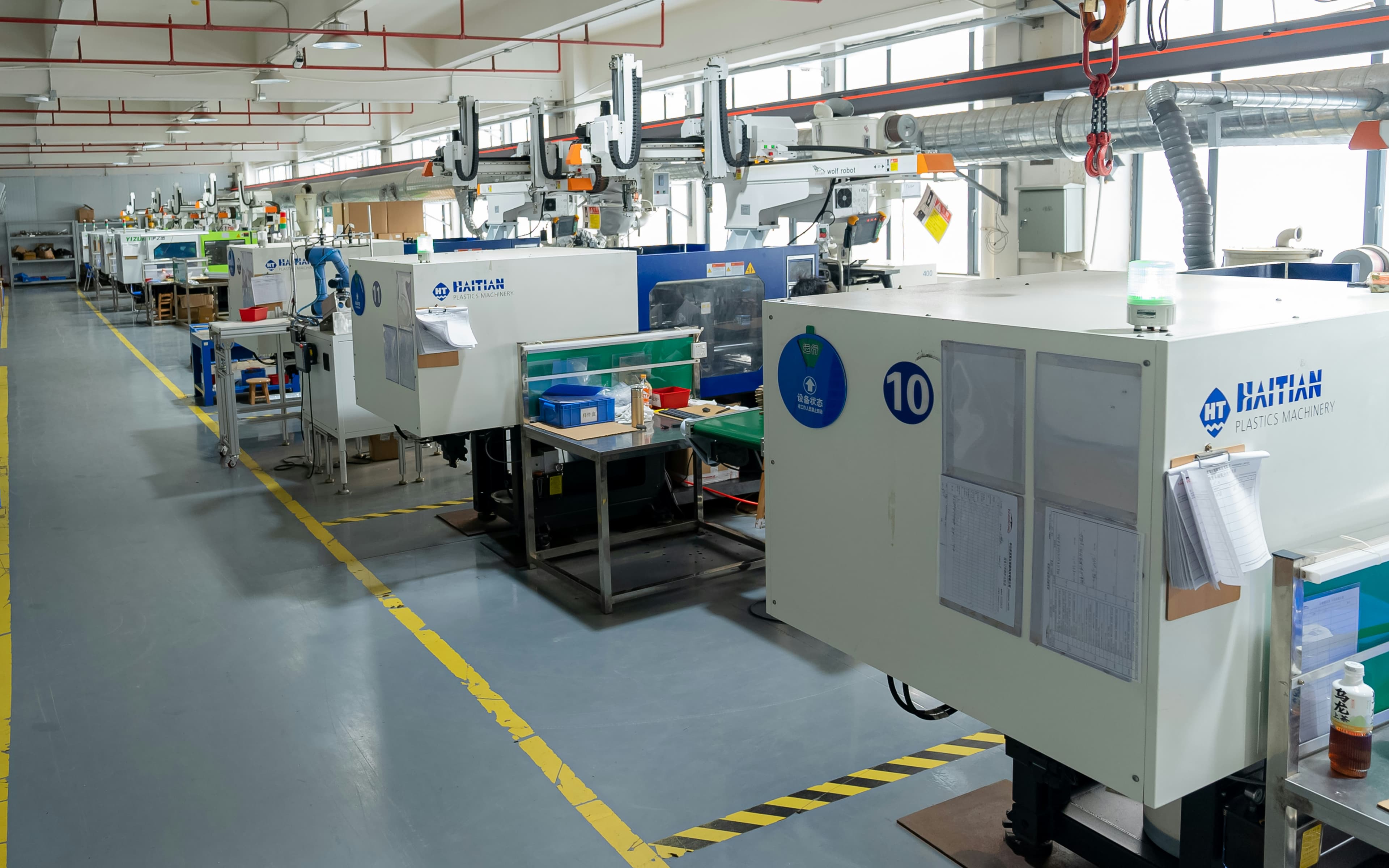 Factory aisle with injection-moulding presses and handling gantries