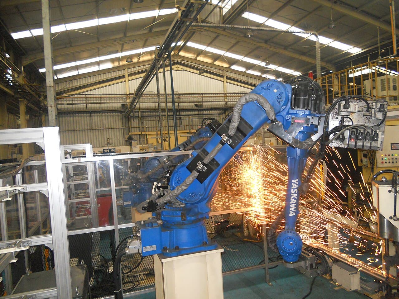 Blue industrial welding robot with sparks at the work area
